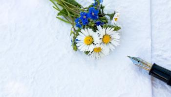 A thank-you note with a tiny bouquet and a fountain pen laying on top.